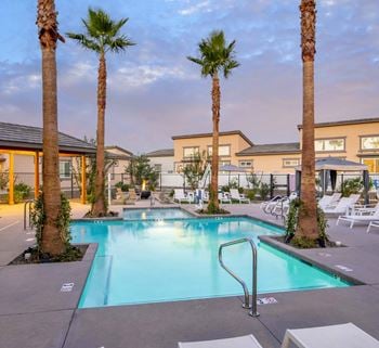 A swimming pool with palm trees and chairs around it